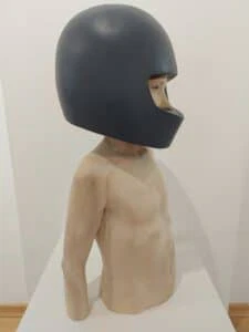 Leo F. Demetz Save in the future Lindenholz, Farbe Höhe 57 cm. Die Skulptur stellt den Torso eines Knaben dar, der einen blauen Motorradhelm trägt.