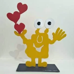 Patrick Preller Love. Objekt aus gelb lackierterm Stahl. Das Monster hält in einer Hand drei rot lackierte Herzen.